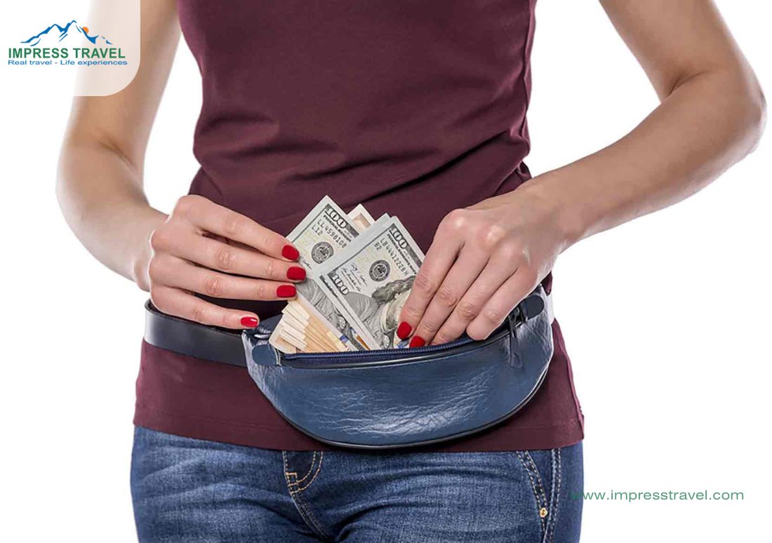 This image depicts a close-up of a woman's torso as she withdraws American dollar bills from a blue fanny pack. Her hands, with red polished nails, carefully handle the cash, emphasizing a sense of security and readiness for financial transactions, such as shopping or currency exchange, while traveling. This visual is likely intended to highlight the practicality of carrying a money belt for safe and convenient access to cash during trips, portrayed against the backdrop of a travel agency logo, suggesting tips for secure travel financing.